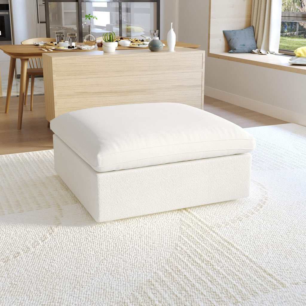 A white, down-filled comfort storage ottoman, placed in a bright living room setting.