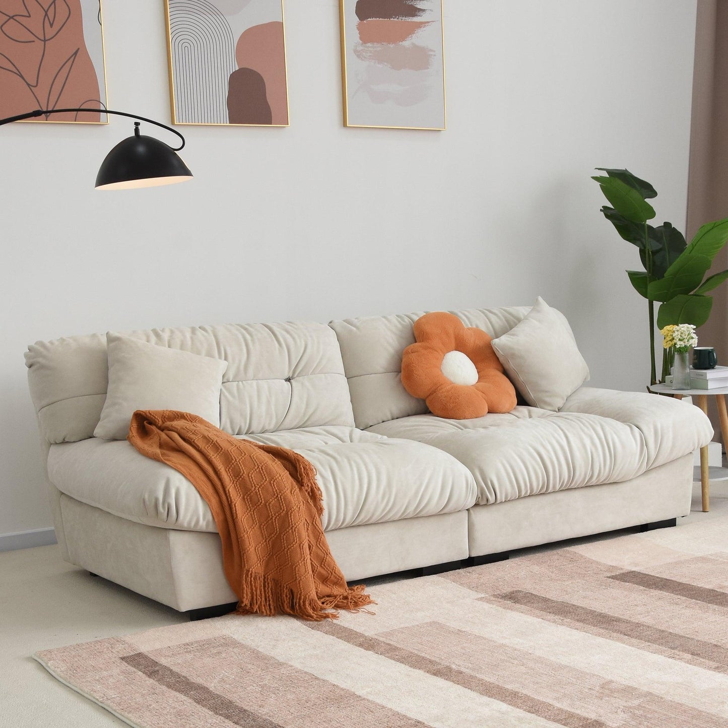 An 89-inch beige microfiber suede sofa with an orange decorations and a solid hardwood frame, presented in a living room setting with minimalistic decor