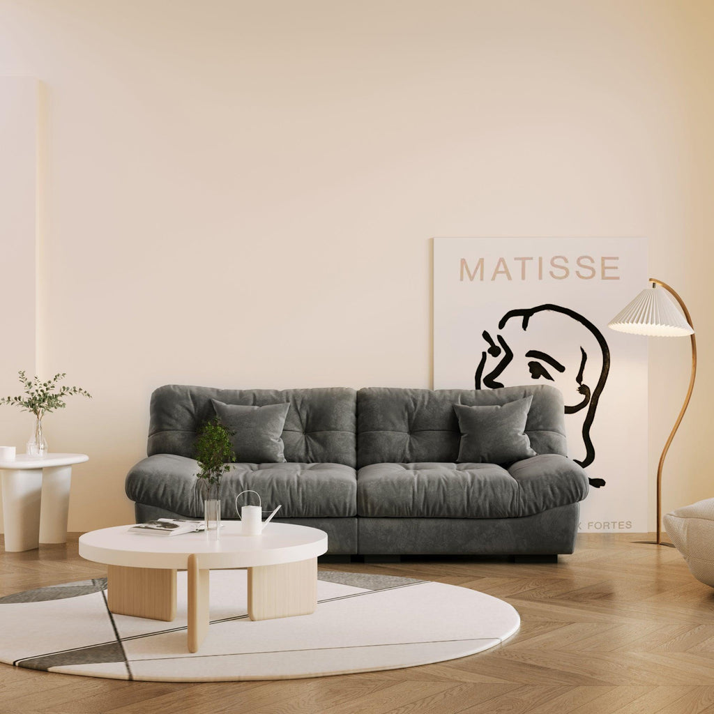 An 89-inch gray microfiber suede sofa in a warm lightning with a solid hardwood frame, presented in a living room setting with minimalistic decor, including a 'Matisse' art print on the wall.
