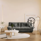 An 89-inch gray microfiber suede sofa in a warm lightning with a solid hardwood frame, presented in a living room setting with minimalistic decor, including a 'Matisse' art print on the wall.