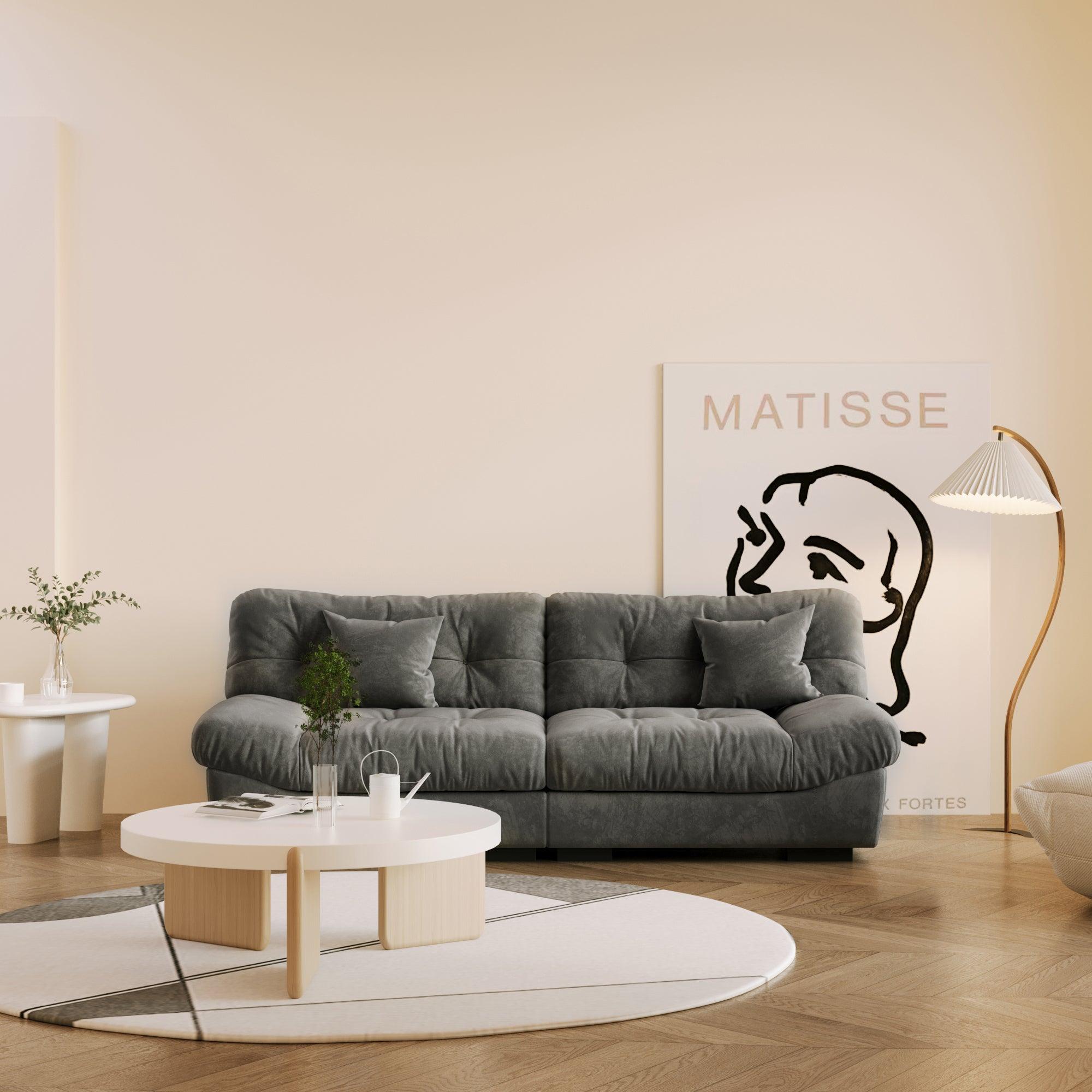 An 89-inch gray microfiber suede sofa in a warm lightning with a solid hardwood frame, presented in a living room setting with minimalistic decor, including a 'Matisse' art print on the wall.