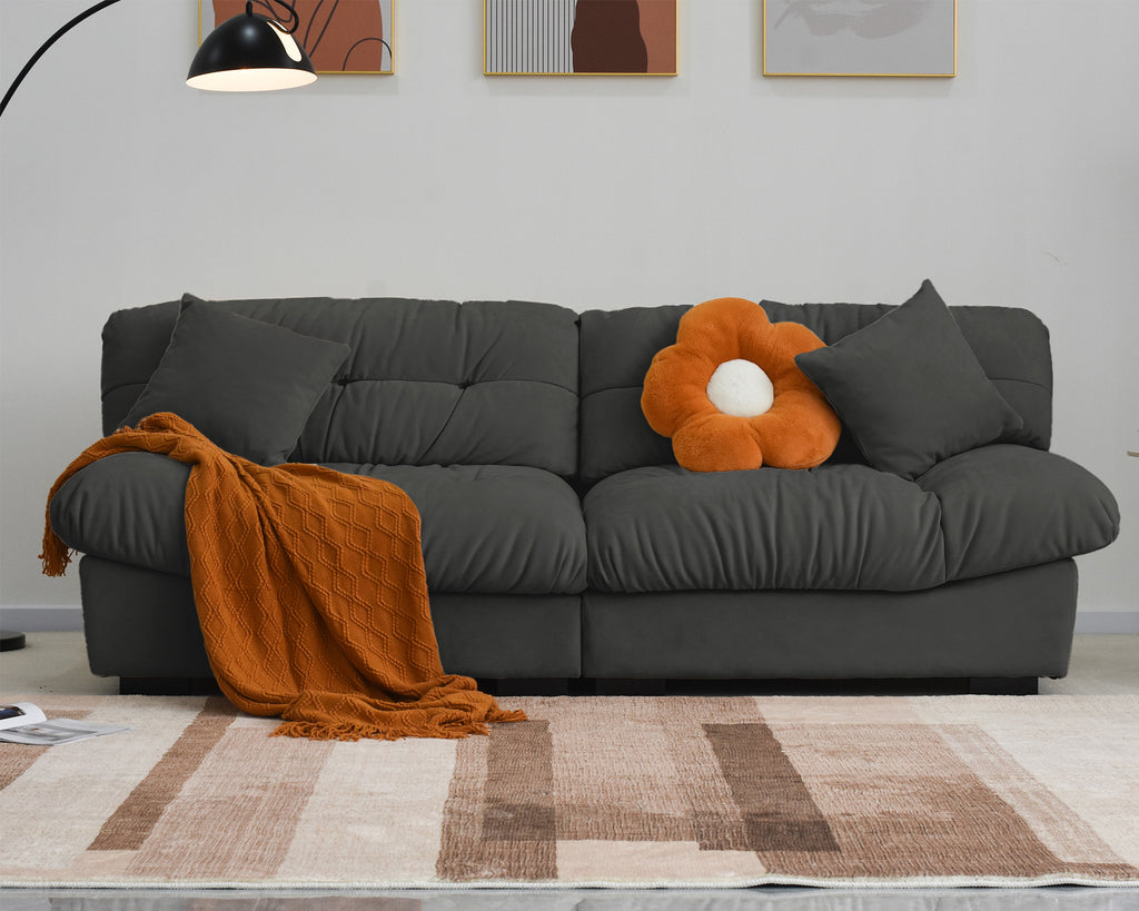 An 89-inch gray microfiber suede sofa with an orange decorations; solid hardwood frame, presented in a living room setting with minimalistic decor