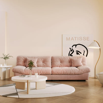 A pink microfiber suede sofa in a warm lightning with splitable seats placed in a room with minimalistic decor, including a 'Matisse' poster on the wall.