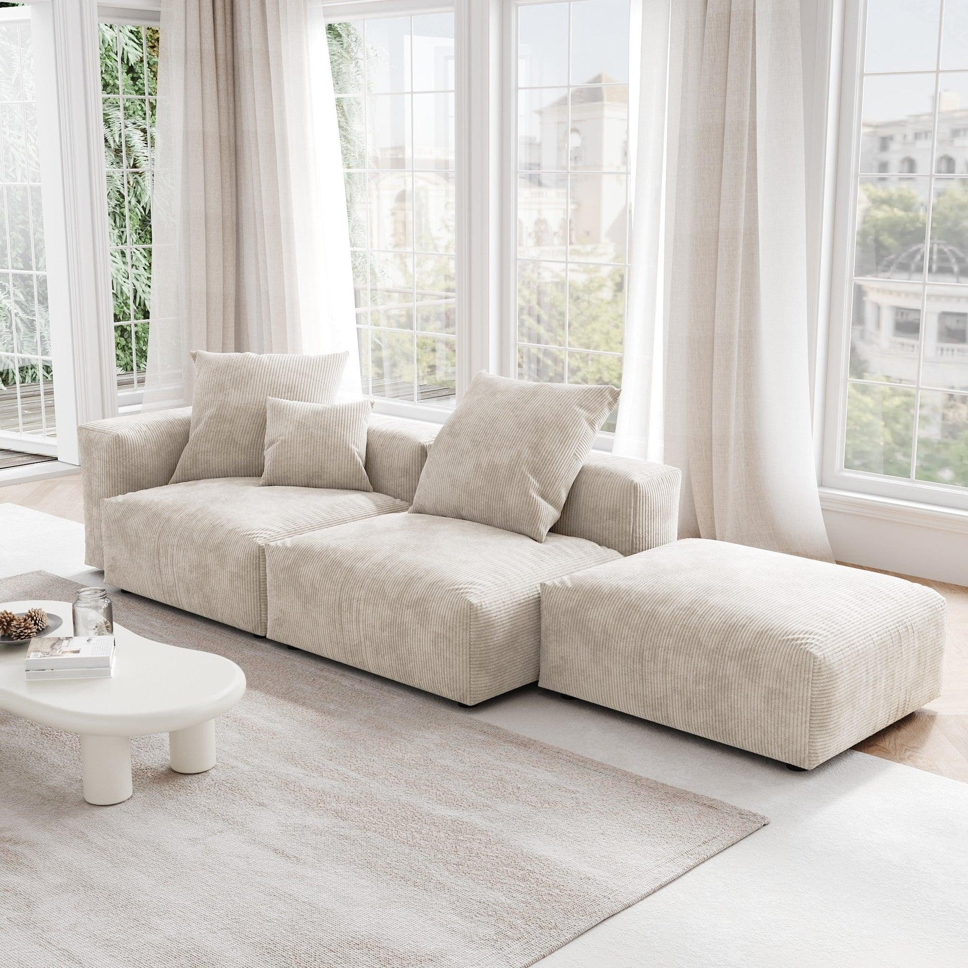 A beige corduroy 3-seat sectional lounger sofa with detachable armrests and removable covers, positioned in a bright room with large windows.