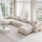 A beige corduroy modular sectional sofa with detachable armrests and removable covers, arranged in a U-shape configuration in a room with a light interior.