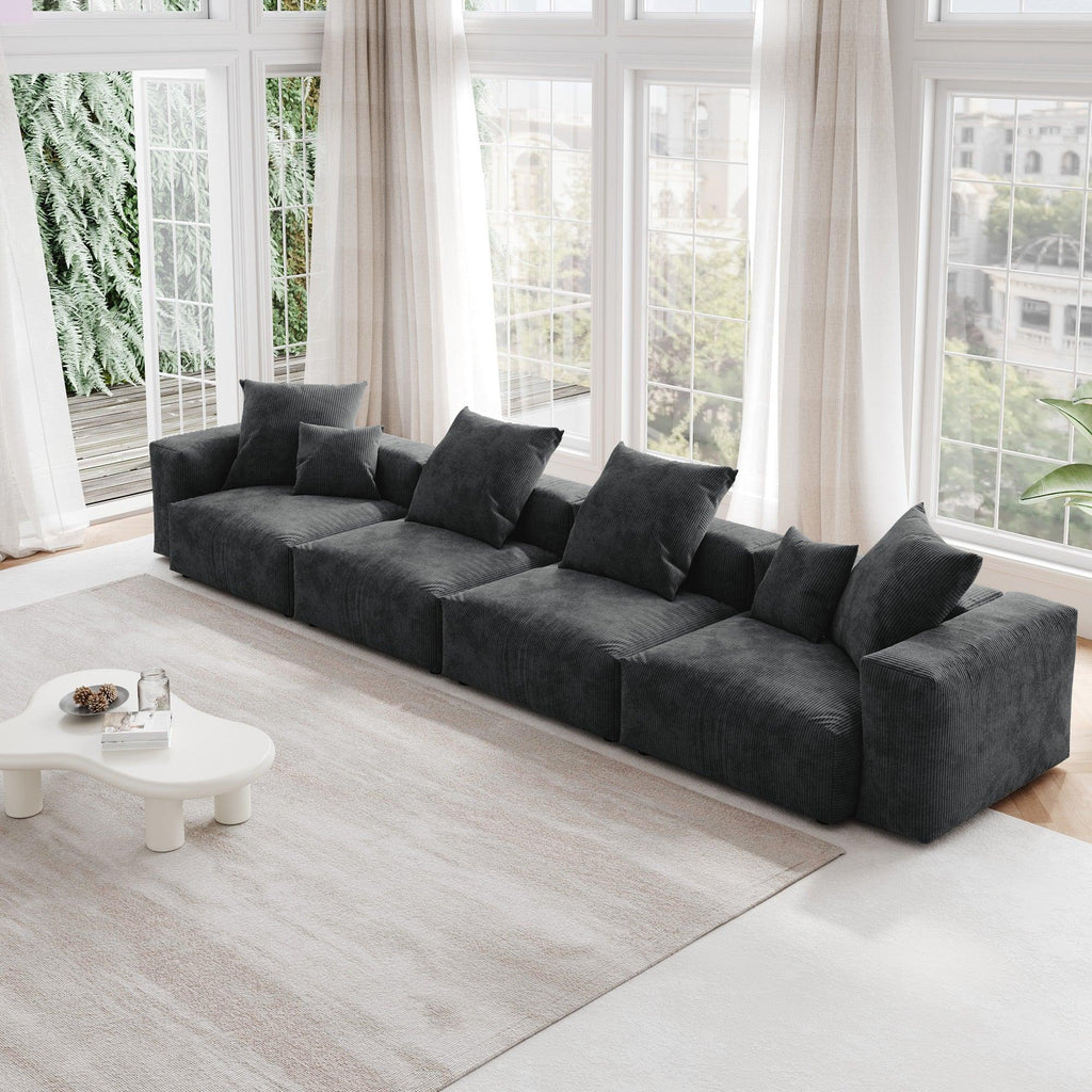 A black corduroy 4-seat sectional modular sofa with detachable armrests and removable covers, designed to seat four people, displayed in a bright room with large windows.