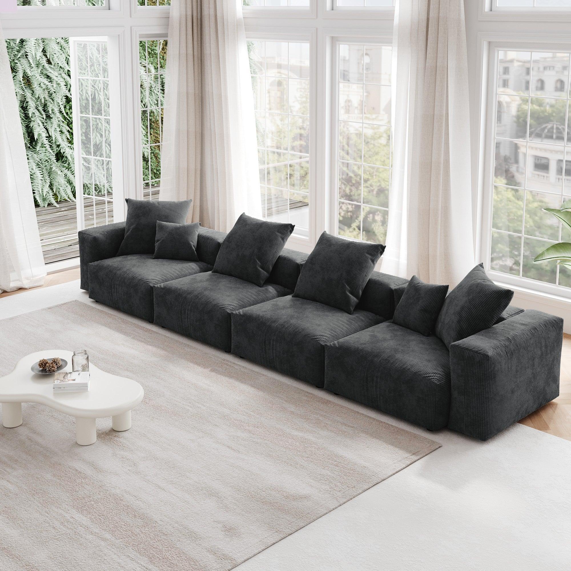 A black corduroy 4-seat sectional modular sofa with detachable armrests and removable covers, designed to seat four people, displayed in a bright room with large windows.