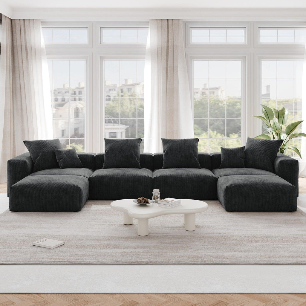 A black corduroy modular sectional sofa with detachable armrests and removable covers, arranged in a U-shape configuration in a room with a light interior.