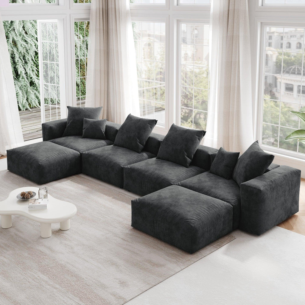 A black corduroy modular sectional sofa with detachable armrests and removable covers, arranged in a U-shape configuration in a room with a light interior.