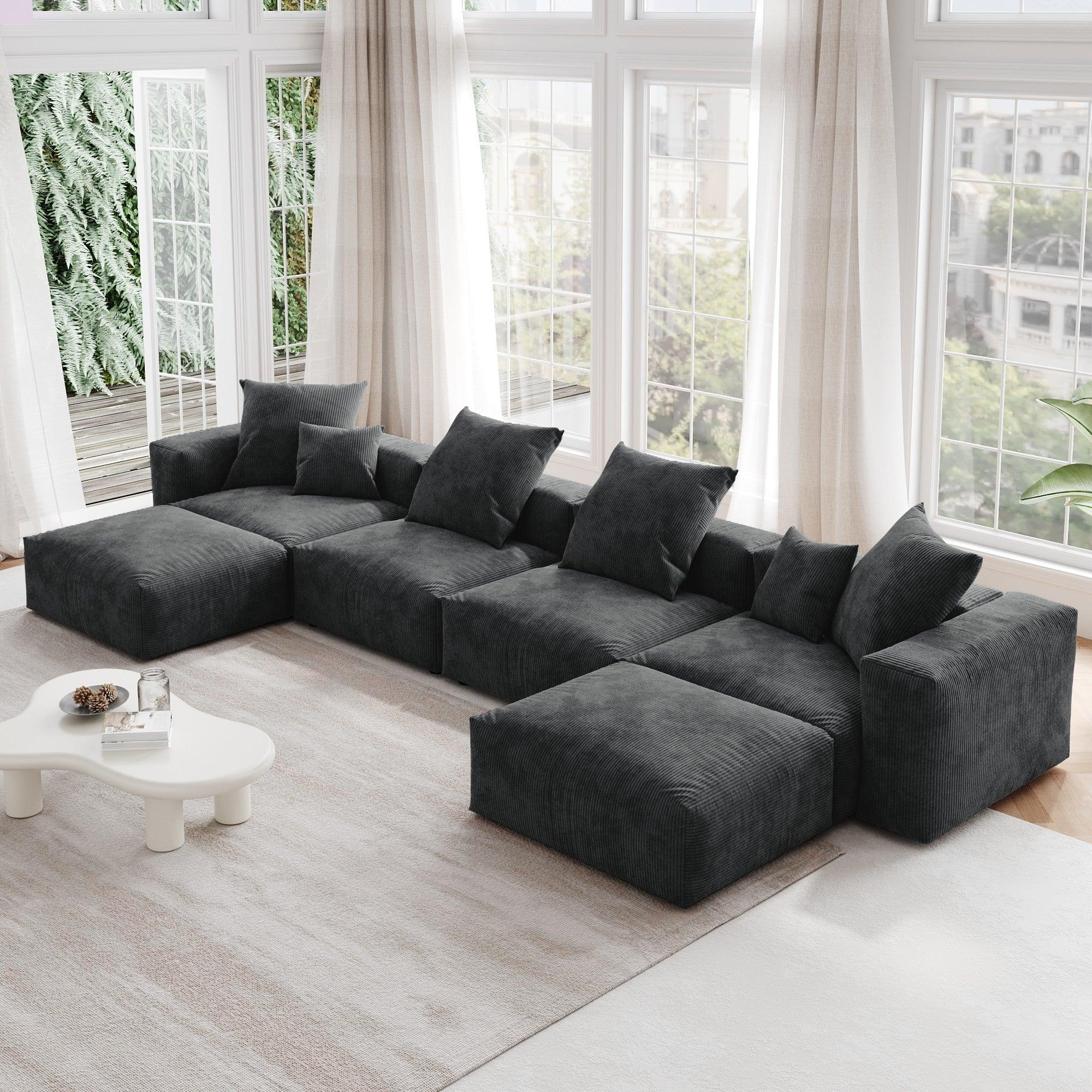 A black corduroy modular sectional sofa with detachable armrests and removable covers, arranged in a U-shape configuration in a room with a light interior.