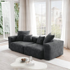 A black corduroy sectional loveseat sofa with detachable armrests and removable covers, positioned in a bright room with large windows.