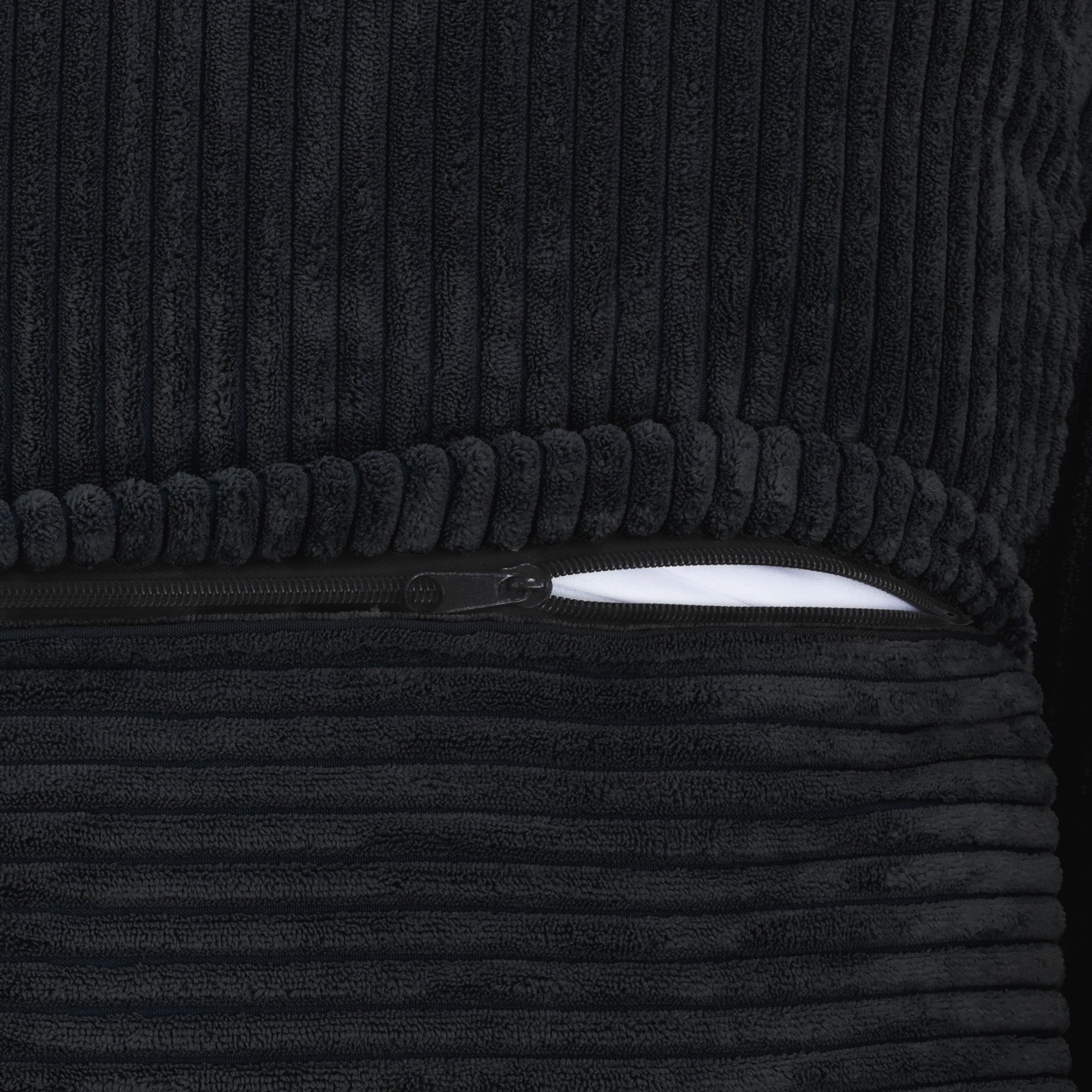 Close-up of a zipper on a cover of a black corduroy sofa