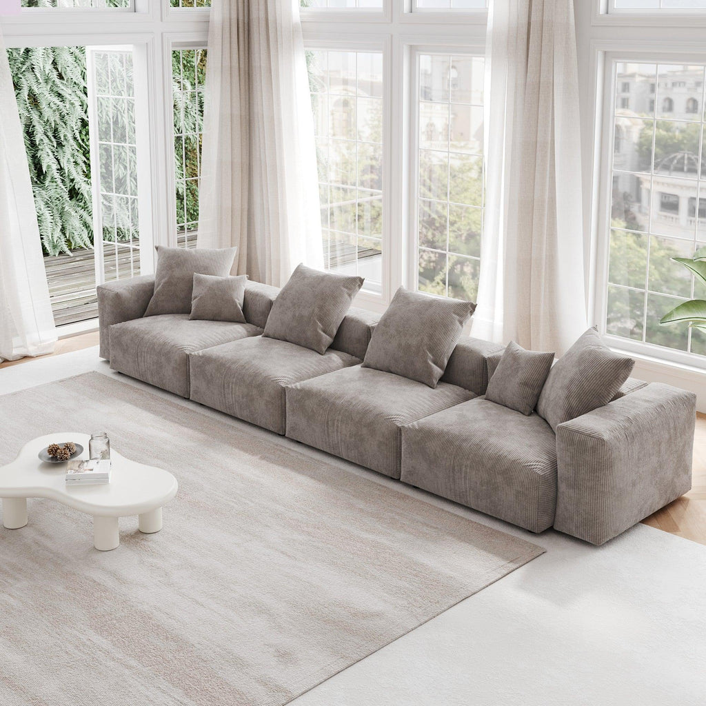 A brown corduroy 4-seat sectional modular sofa with detachable armrests and removable covers, designed to seat four people, displayed in a bright room with large windows.