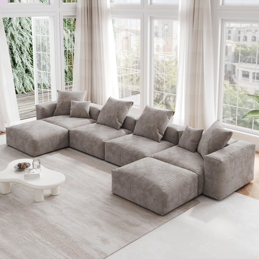 A brown corduroy modular sectional sofa with detachable armrests and removable covers, arranged in a U-shape configuration in a room with a light interior.