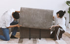 Two people assembling brown corduroy sofa