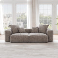 A brown corduroy sectional loveseat sofa with detachable armrests and removable covers, positioned in a bright room with large windows.