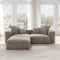 A brown corduroy sectional loveseat sofa with ottoman, detachable armrests, and removable covers, featuring a chaise lounge configuration placed in a room with large windows.