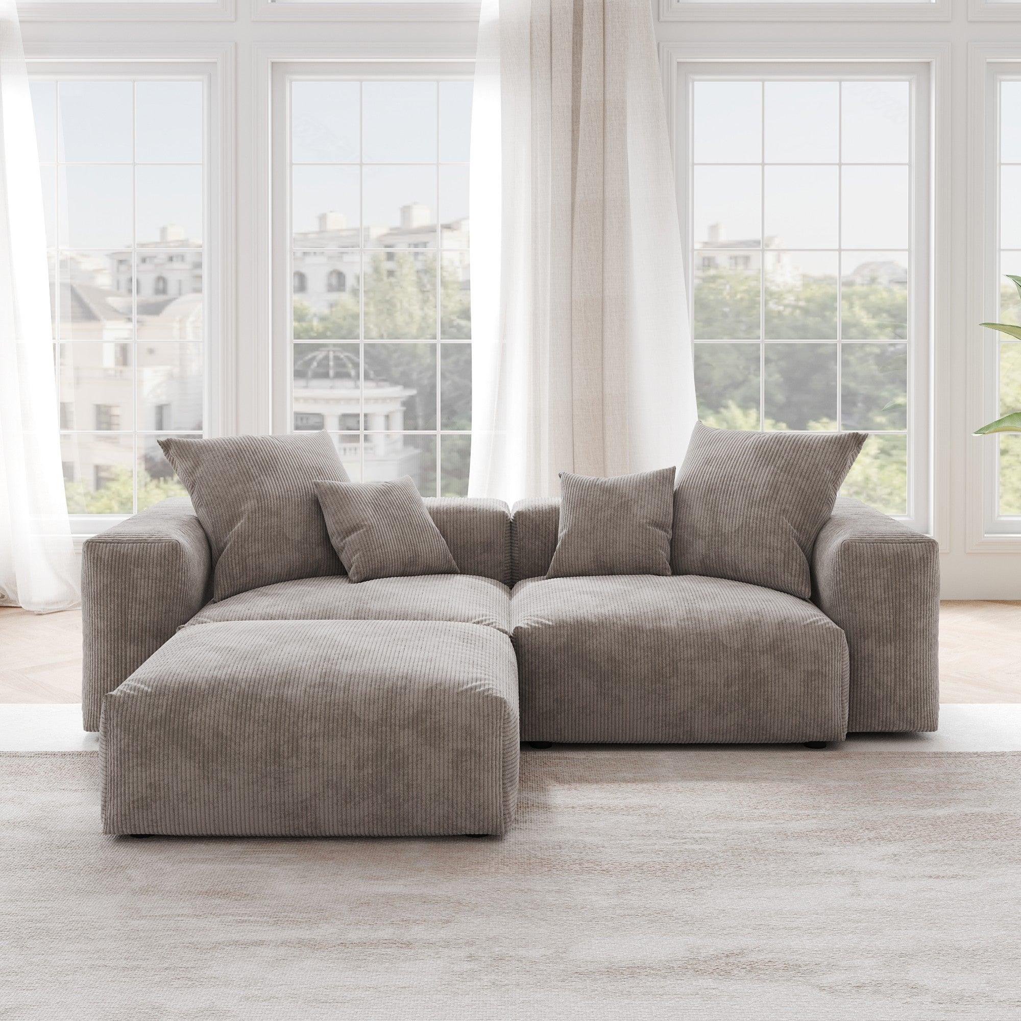 A brown corduroy sectional loveseat sofa with ottoman, detachable armrests, and removable covers, featuring a chaise lounge configuration placed in a room with large windows.