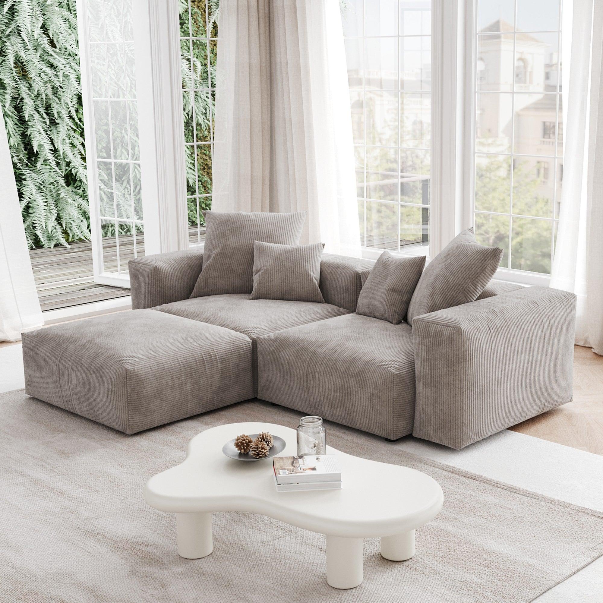 A brown corduroy sectional loveseat sofa with ottoman, detachable armrests, and removable covers, featuring a chaise lounge configuration placed in a room with large windows.