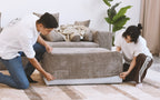Two people putting brown corduroy cover on a sofa frame