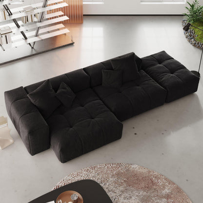 A modern, black 3-seat modular lounger sofa in white color with wide armrests and multiple accent pillows, arranged in a living room setting.