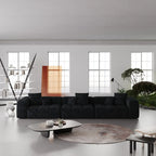 Modern living room with a black 3-seater sofa, coffee table, and decorative elements.