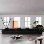 Modern living room with a large black 4-seater sofa, round coffee table, and decorative elements.