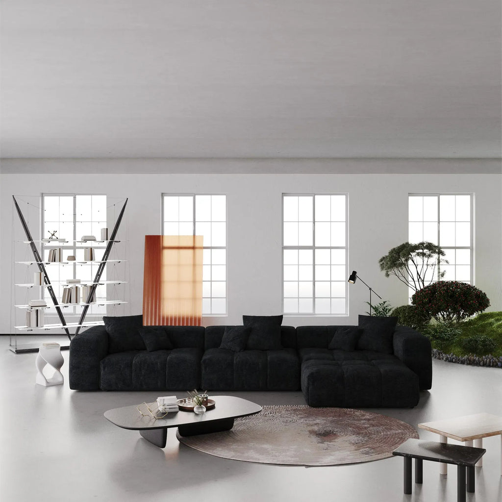 Modern living room with a black L-shaped sectional sofa, coffee table, and decorative elements.