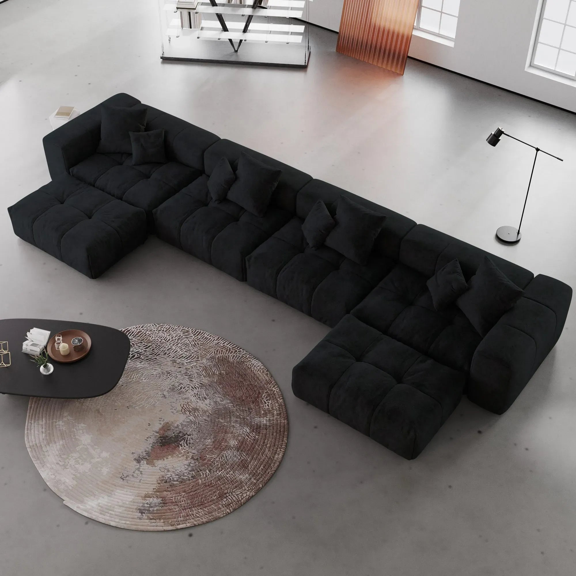 Black U-shaped sectional sofa in a modern living room with a round rug and coffee table.