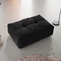Black ottoman on a textured surface with a neutral background