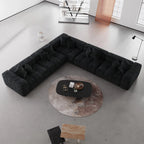 Modern black V-shaped corner sectional sofa in a minimalistic living room with a round coffee table.