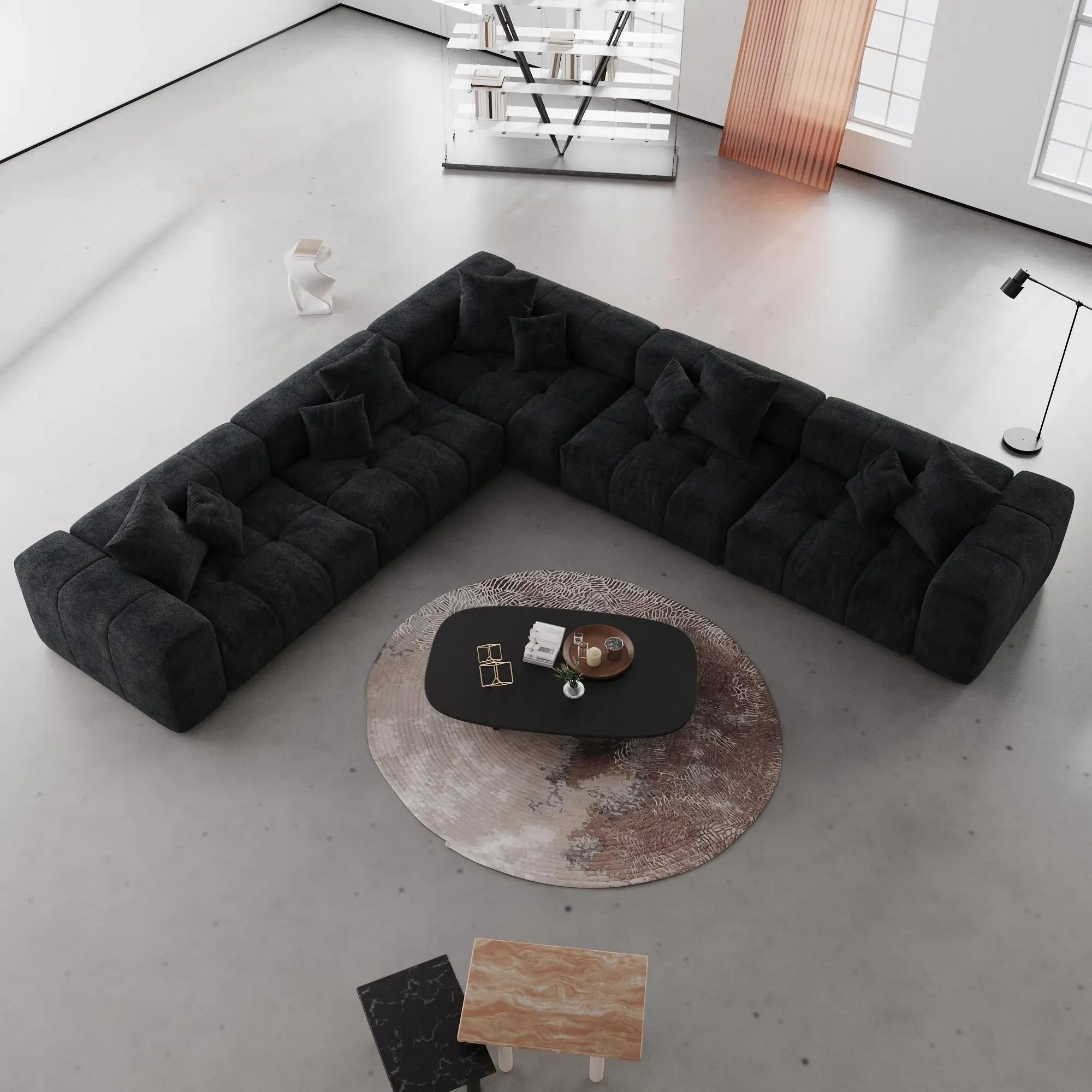 Modern black V-shaped corner sectional sofa in a minimalistic living room with a round coffee table.
