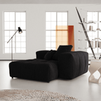 Black sectional module in a modern living room with large windows and minimal decor.