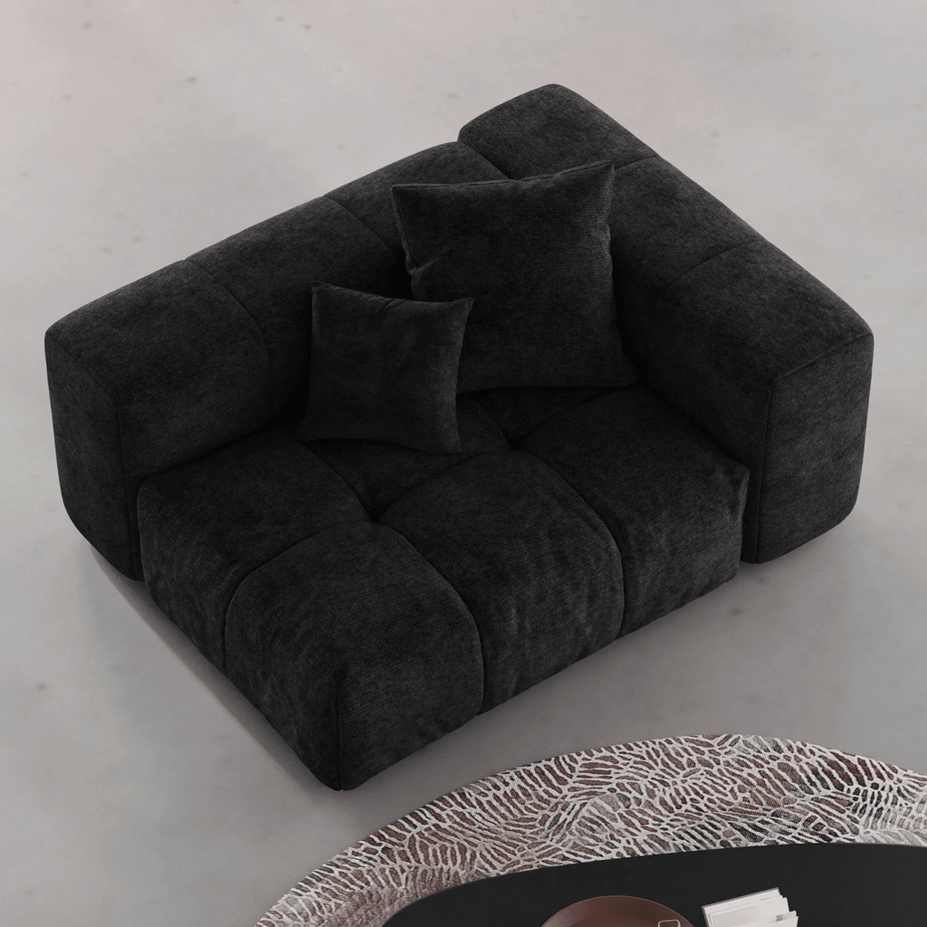 Black tufted left end chair on a light gray floor with a patterned rug.