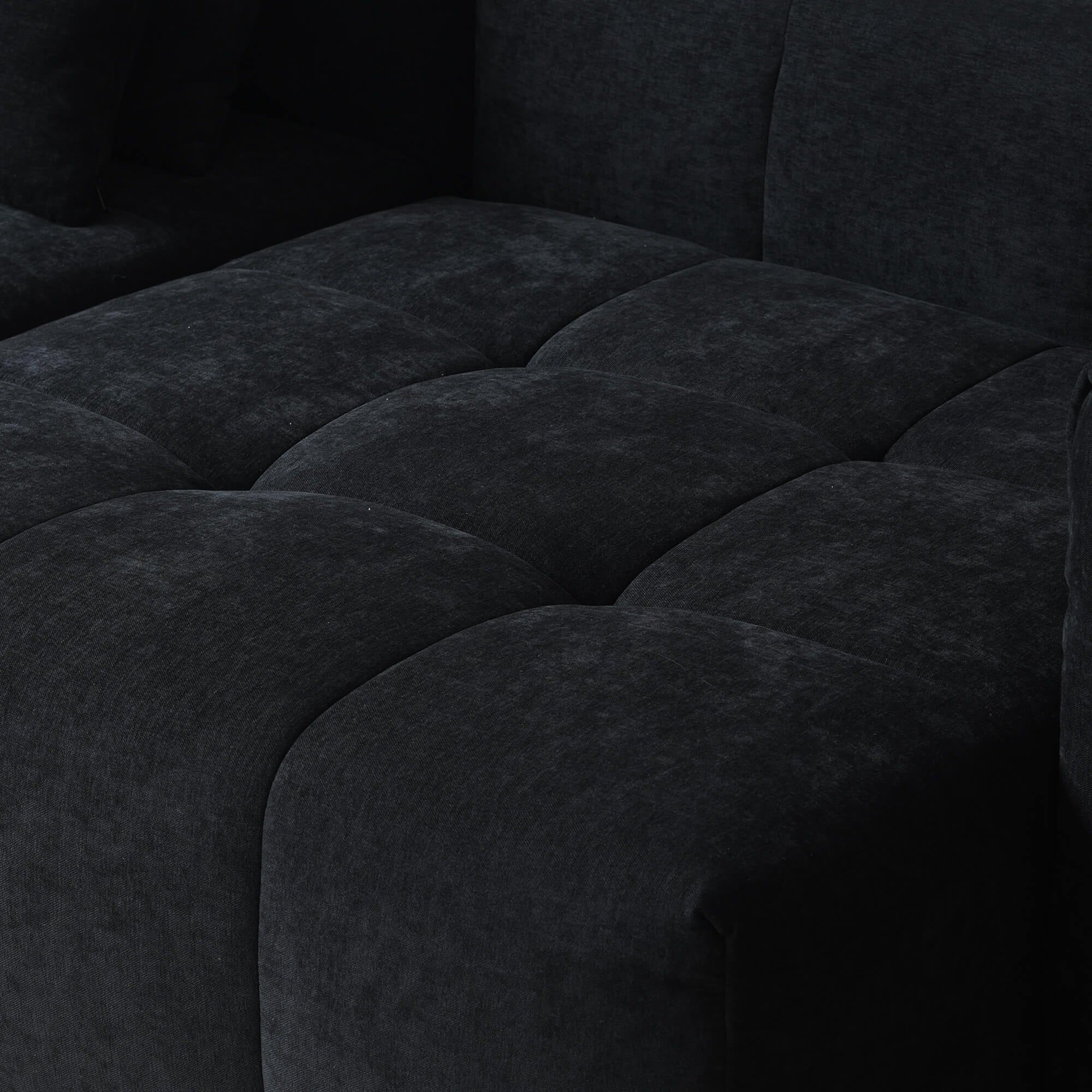 Close-up of a seat of a black tufted sofa