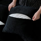 Person unzipping a pillow cover of a black sofa