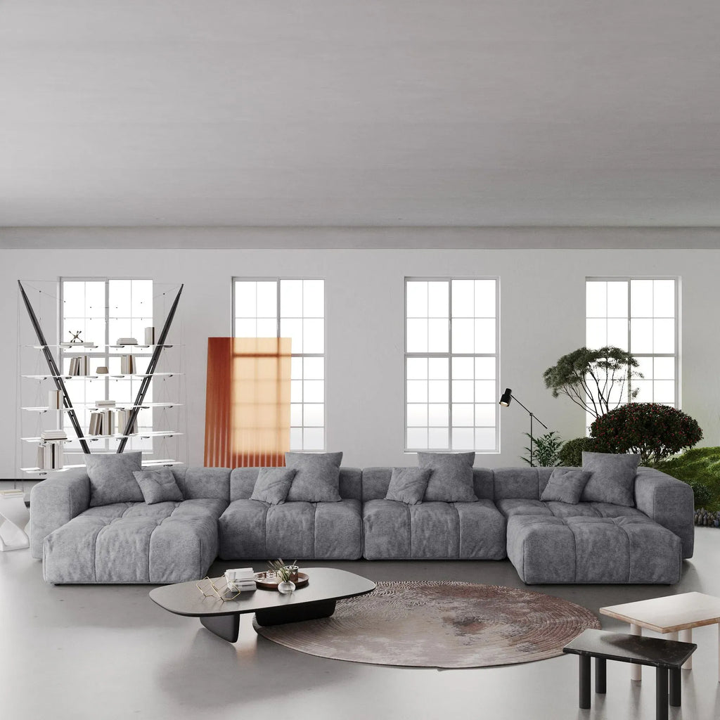 Modern living room with a large gray U-shaped sectional sofa, coffee table, and decorative elements.