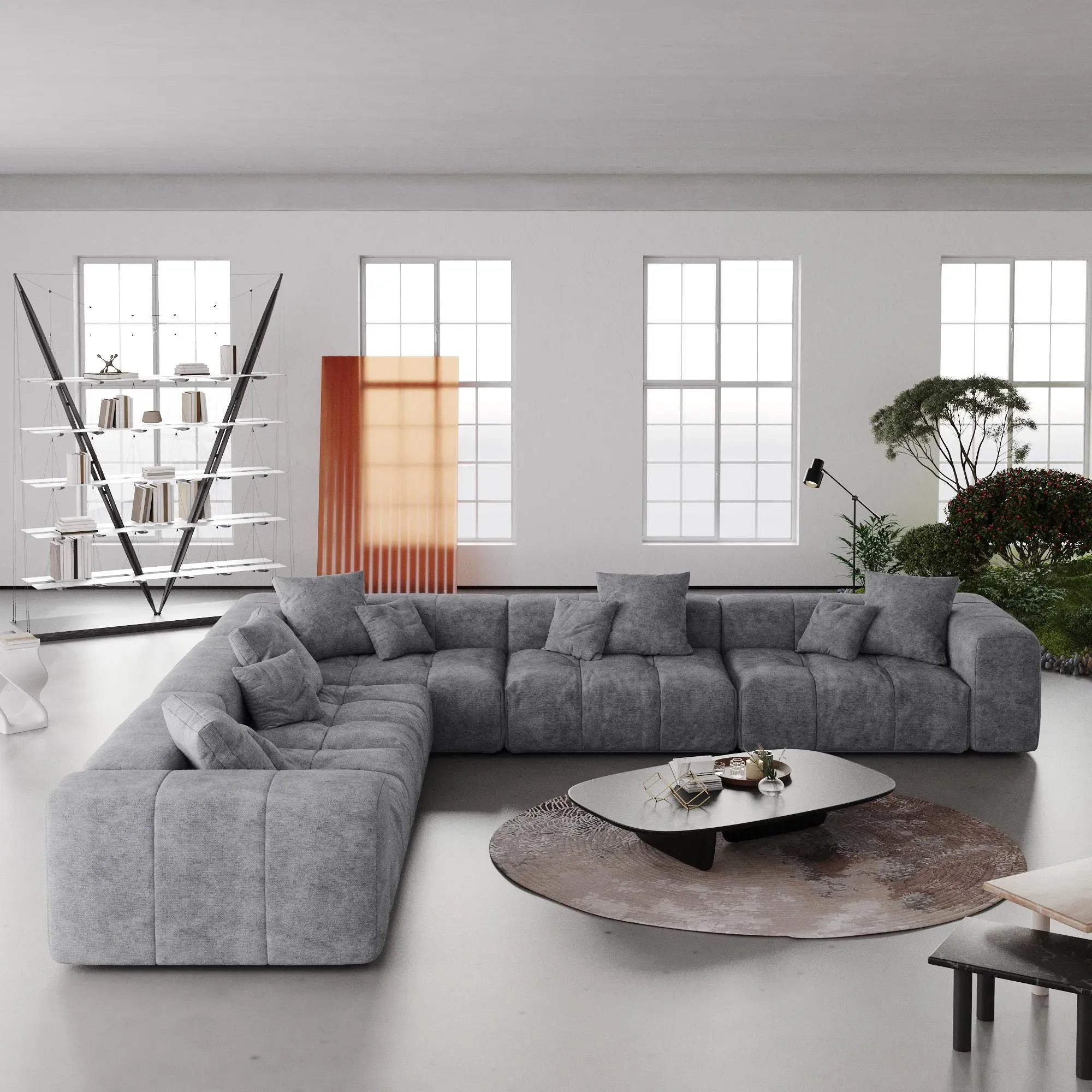 Gray V-shaped corner sectional sofa in a modern living room with large windows and minimal decor.