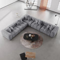 Gray V-shaped corner sectional sofa in a modern living room with a round coffee table.