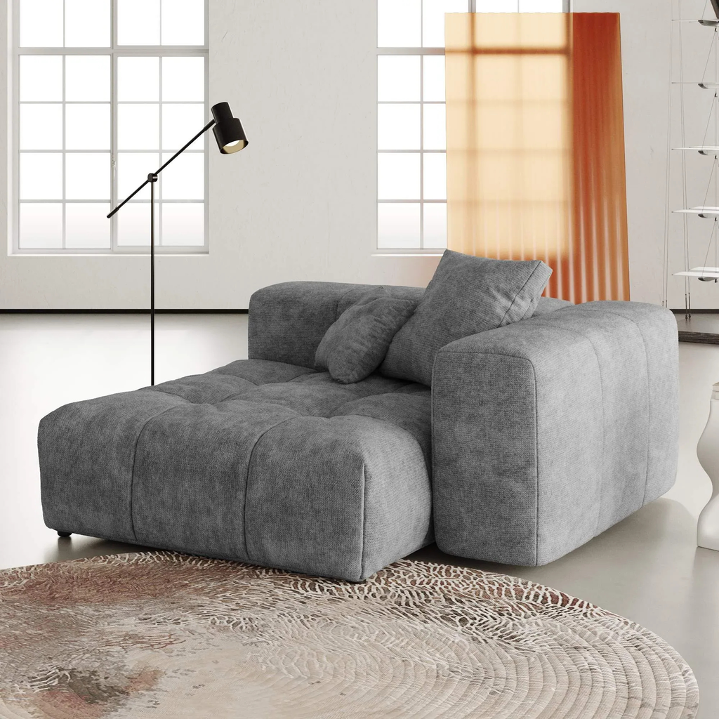 Gray linen deep end chair in a modern living room with a lamp and window in the background.