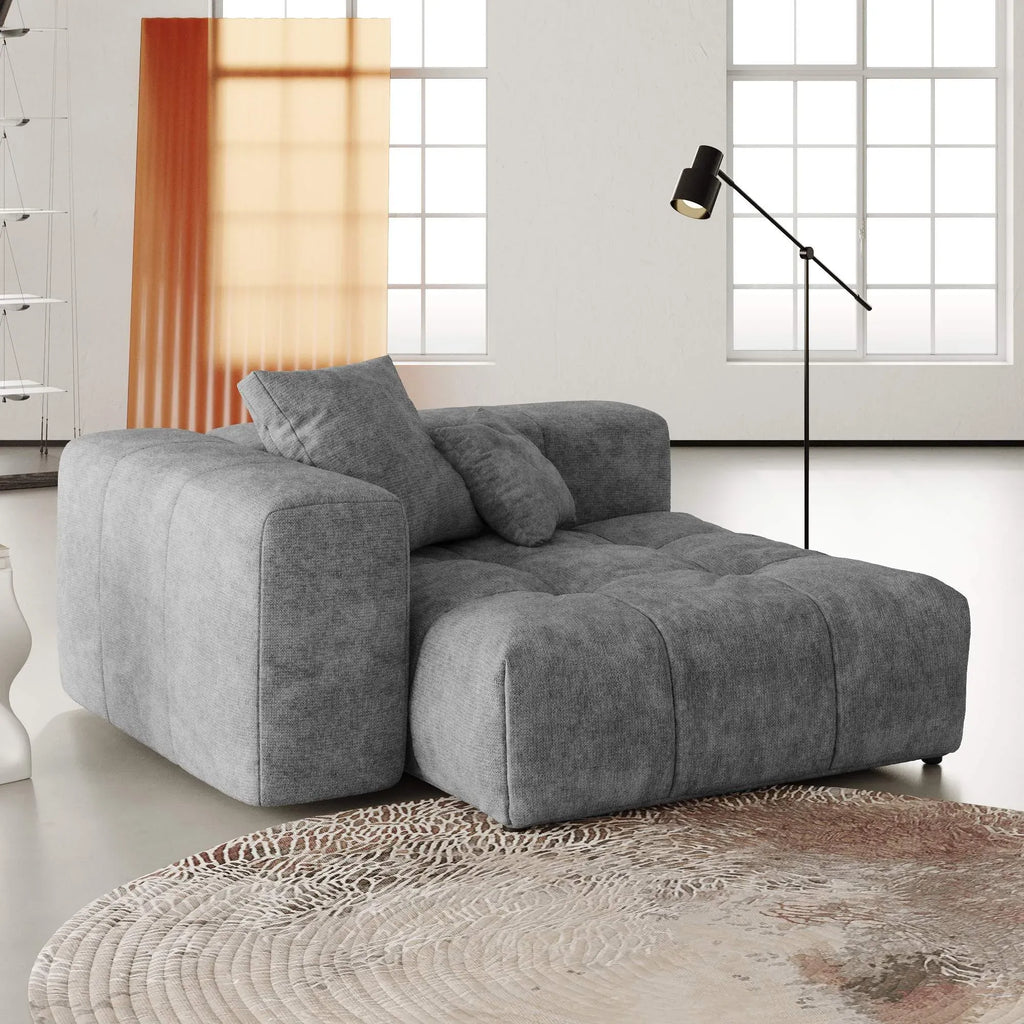 Gray modular chair in a modern living room with a lamp and window in the background.