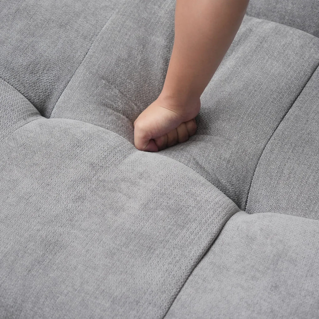 Close-up of a hand pressing on a seat cushion of a gray sofa