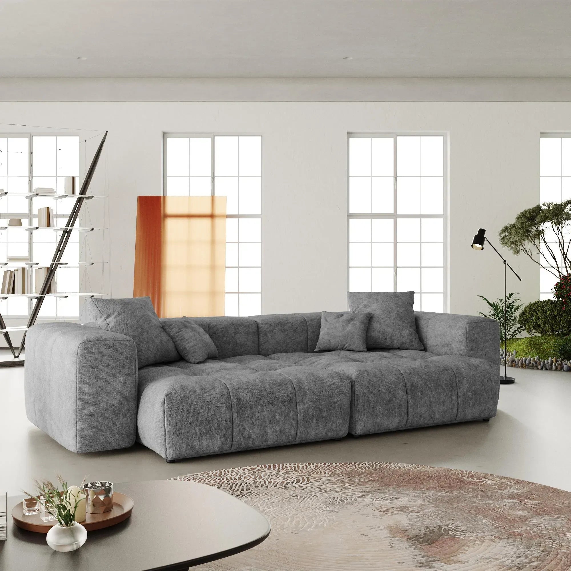 Gray sectional loveseat sofa in a modern living room with large windows.
