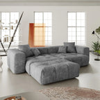 Gray sectional loveseat sofa with ottoman in a modern living room with large windows.
