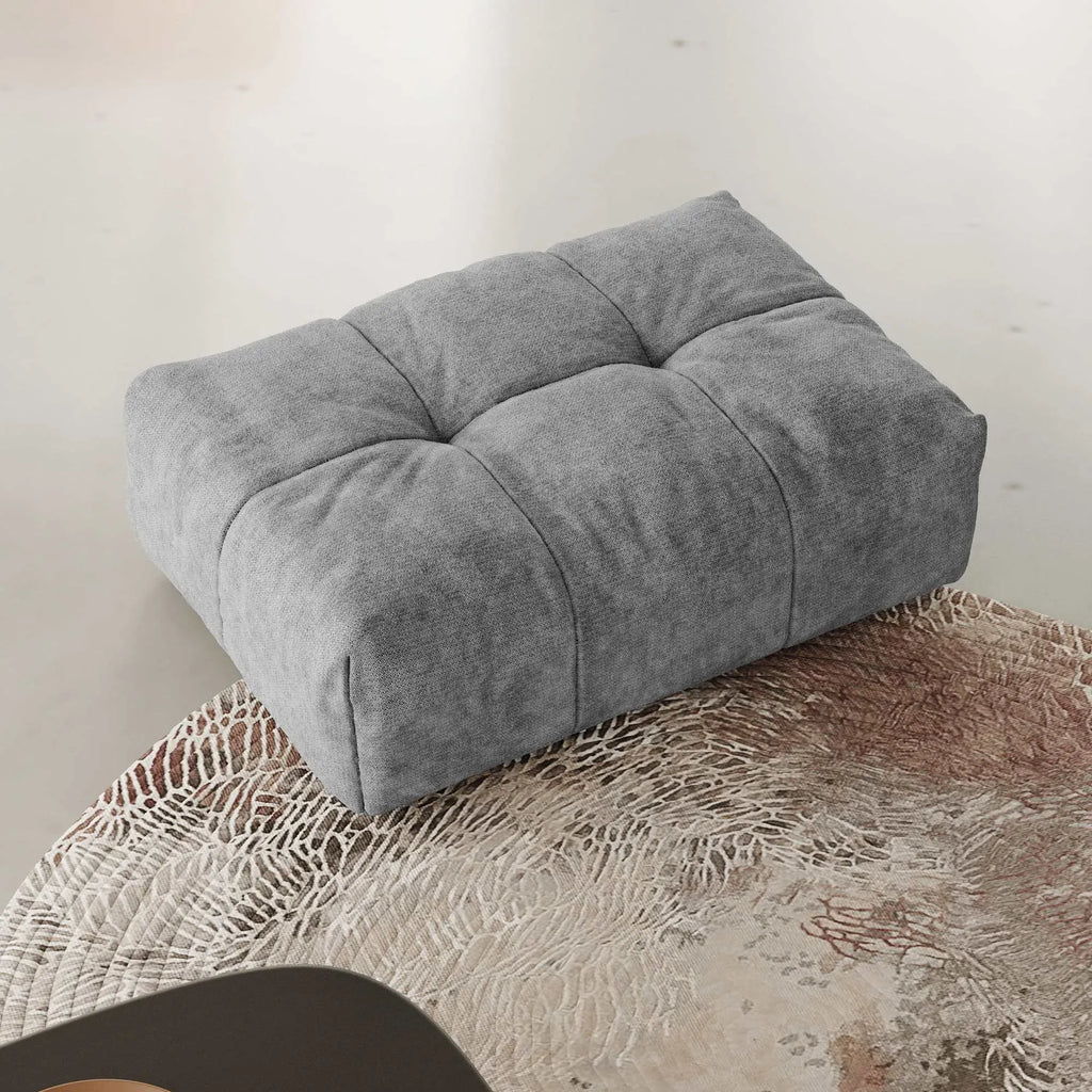 Gray ottoman on a textured surface with a neutral background