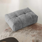 Gray ottoman on a textured surface with a neutral background