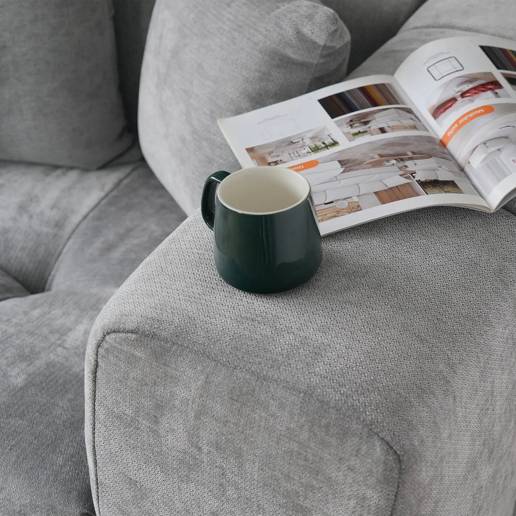 Green mug on a gray sofa with an open magazine