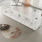 Modern white 4-seater sofa in a minimalistic living room with a round rug and coffee table.
