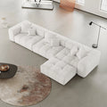 Modern white L-shaped sectional sofa in a minimalistic living room with a round rug and coffee table.