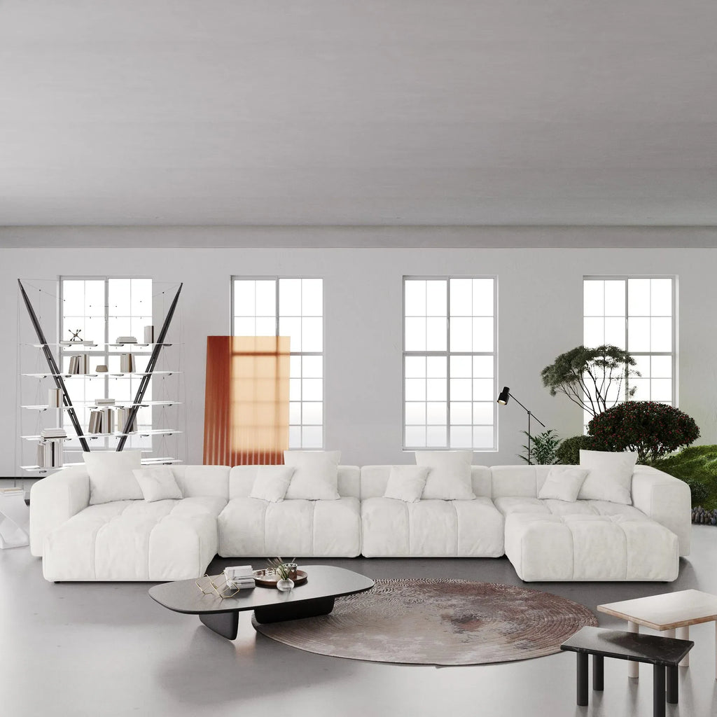Modern white U-shaped sectional sofa in a minimalistic living room with large windows.